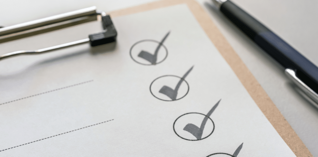 תקריב של רשימת ביקורת על לוח כתיבה, המציגה ארבע תיבות מסומנות ברצף — מושלמת לסינון תוכן לילדים. עט מונח בסמוך, בצד ימין של לוח הכתיבה.